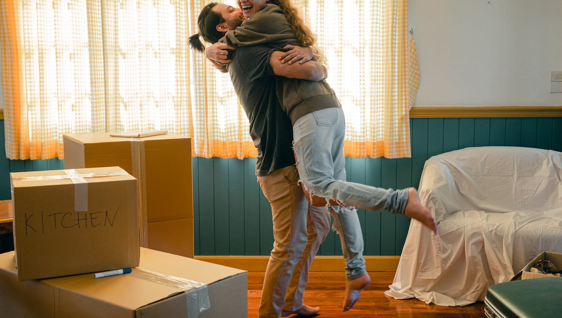 cheerful couple hugging and unpacking carton boxes