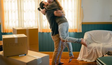 cheerful couple hugging and unpacking carton boxes