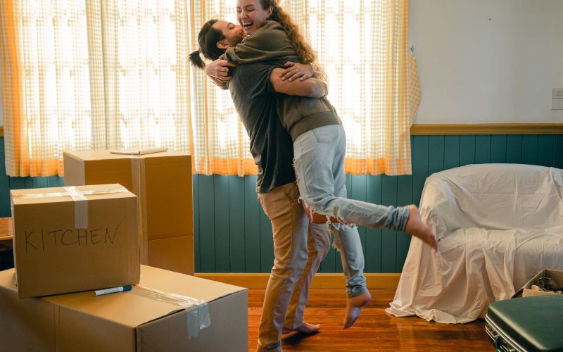 cheerful couple hugging and unpacking carton boxes