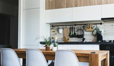 brown wooden dining table with white chairs near kitchen