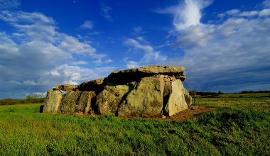 a large rock sitting on top of a lush green field