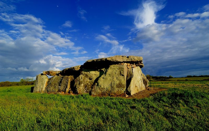 a large rock sitting on top of a lush green field