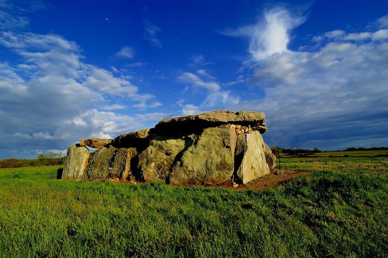 a large rock sitting on top of a lush green field