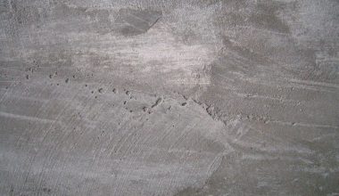 Close-up van een glad afgewerkte leemstuc muur met een warme, aardse textuur