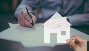 Starter tekent koopcontract voor eerste huis aan tafel bij makelaar