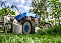 Tuineigenaar die voegen wiedt tussen terrastegels in een achtertuin