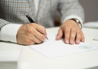 Persoon die een contract ondertekent voor een badkamerverbouwing aan een tafel met offertes